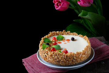 Cheesecake with cream cheese and citrus zest topped with mint, chocolate and jelly balls against the black background