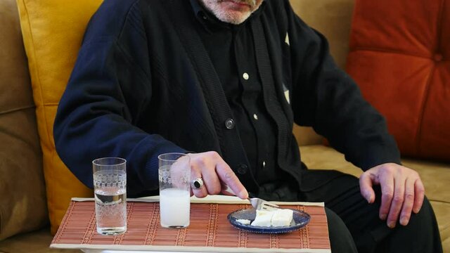 Portrait of an old man eating white cheese with the Raki, Unsweetened, anise flavored alcoholic drink that is popular in Turkey, Iran and Balkan countries as an aperitif. It is often served in flat cy