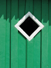 A small diamond window in a green wooden wall, Suwalki region, Poland