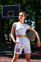 Young woman with a basketball ball posing on the playground