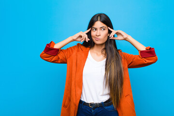 young pretty latin woman looking concentrated and thinking hard on an idea, imagining a solution to...