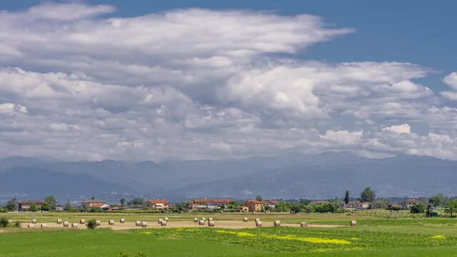Beautiful landscape in the Tuscan countryside between the provinces of Pisa, and Lucca with hay bales in the foreground and Mount Abetone in the background, Italy, time lapse motion