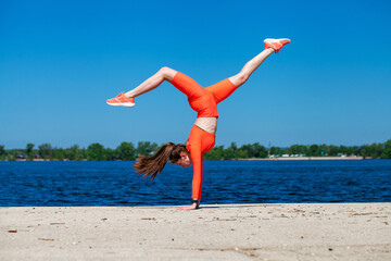 Young athletic girl does physical exercises on the banks of the Volga River
