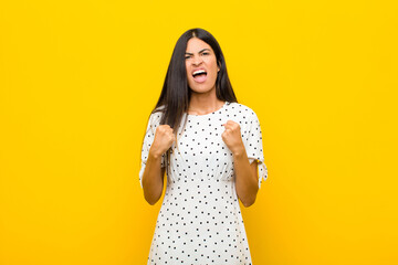 young pretty latin woman shouting aggressively with annoyed, frustrated, angry look and tight...