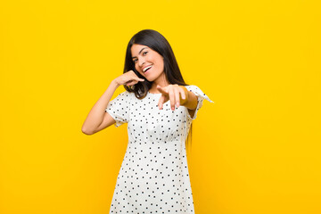 young pretty latin woman smiling cheerfully and pointing to camera while making a call you later...