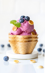 Waffle cup with blueberrie ice cream topped with miniature pancakes