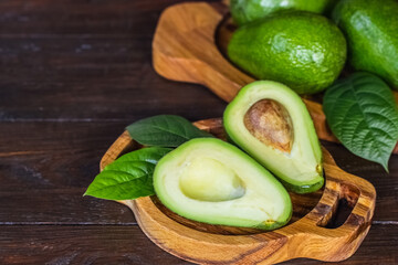 fresh avocados. whole avocados, avocado halves and leaves on a wooden background. avocado on the table.
