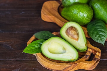 fresh avocados. whole avocados, avocado halves and leaves on a wooden background. avocado on the...