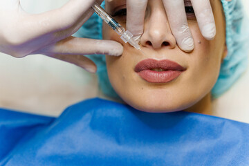 Closeup lips augmentation injections for attractive girl. Plastic surgeon does injection in lip in...