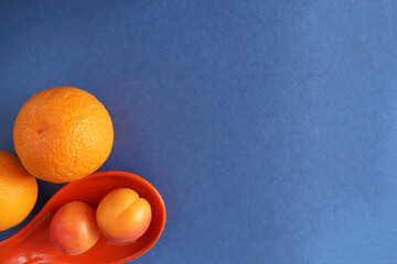 Fruit on a blue background and place for text. Fresh orange and apricots with space for text.