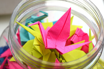 colorful origami cranes on top jar white