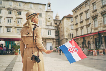 Fototapeta na wymiar Enjoying vacation in Croatia. Young traveling woman with national croatian flag walking on Split Old Town.