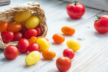 red cherry tomatoes in basket on wooden table close-up