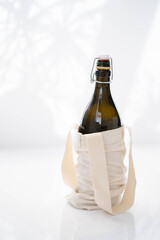 Reusable glass bottle in cotton shopping bag on a white background. Eco-friendly , top view. Zero waste eco shop banner design

