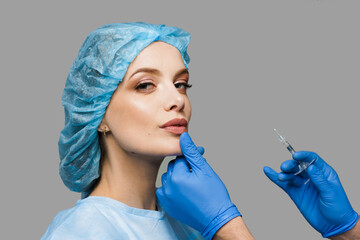 Lips augmentation injections for attractive girl on white background. Plastic surgeon does...