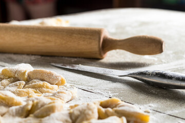 kitchen table. Sprinkled with flour. On it are dough products. Brushwood. Close-up