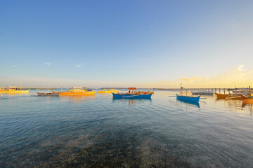 Beautiful colorful sunset on the seashore with fishing boats. Philippines, Siargao Island.