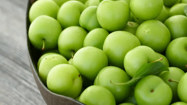 a basket full of green sour plums, a lot of sour plums from the season,