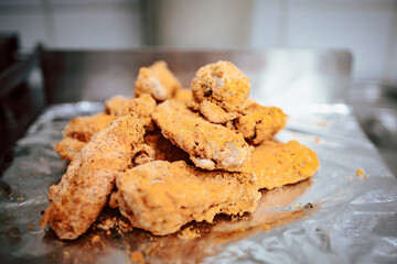 Freshly prepared fried chicken nuggets on alu foil. Restaurant meal preparation