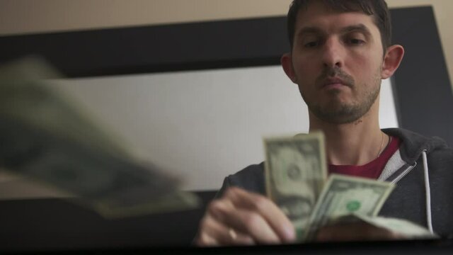 High quality slow motion close-up 4k video of a young man counting american dollars cash and coins. US money, financial crisis and lockdown. Salary in america.