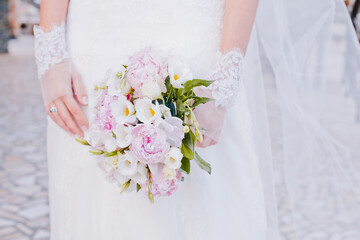 delicate bridal bouquet  in the hands of the bride on a white dress