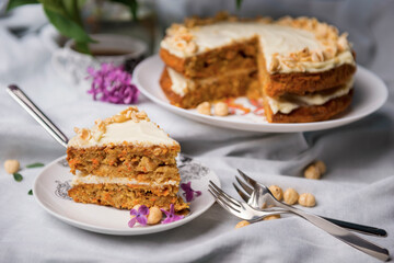 Piece of carrot cake with carrot cake and a cup of tea on the background
