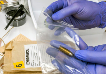 Scientific police picking up bullet in evidence bag, conceptual image