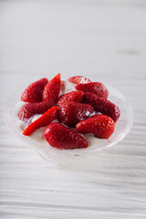 Strawberry dessert in a plate with ice cream and cream on a white wooden background