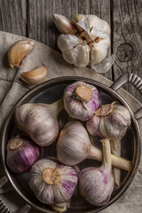 Garlic in a dish on an old wooden table. Vintage, rustic style.