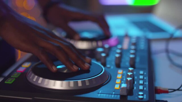  Close up of hands of unrecognizable black DJ using controller and playing music at party