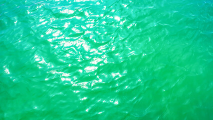 Turquoise background, texture of water surface with sunlight reflections