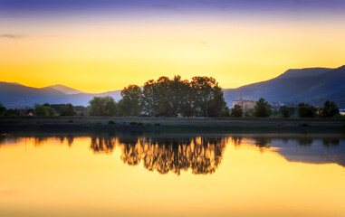 Perfect golden hour sunset over calm, reflective lake with gradient in the sky and silky, glowing water in Pirot, Serbia