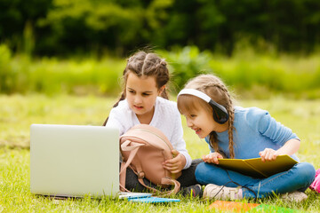 Two beautiful sisters do their homework during quarantine. Children use gadgets for learning....