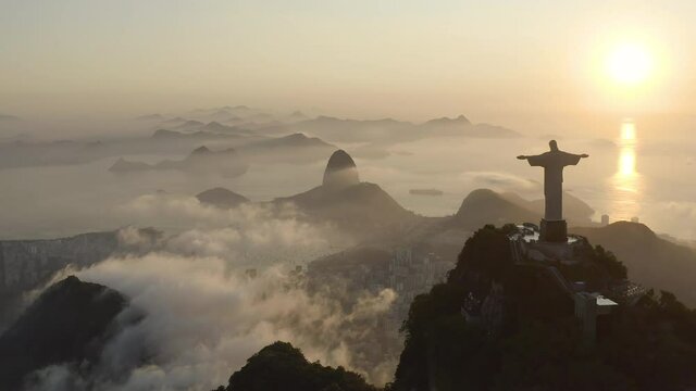 Amazing, aerial shot of a Christ the Redeemer silhouette during summer sunrise over the clouds in Rio de Janeiro Brazil
