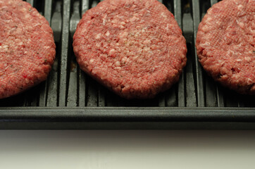 Seasoned beef burgers with a pinch of salt and black pepper on the grill