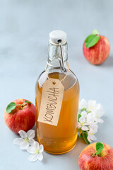 Homemade fermented kombucha drink in a glass bottle and fresh apples on a light gray stone table. A healthy probiotic drink. Copy space.