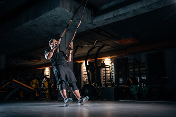 Obraz na płótnie Canvas young man has crossfit workout with trx in modern gym