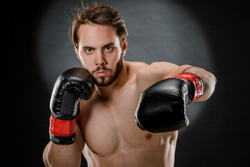 A man in Boxing gloves. A man Boxing on a black background. The concept of a healthy lifestyle