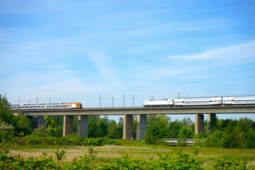 Schienenverkehr: Personenzüge begegnen sich auf einer Brücke (Mobilität, Verkehrswende),...