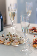 Reserved table with various snacks at the welcome party. Canape and sandwiches, wine.
