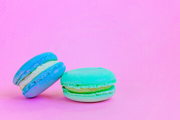 Sweet almond colorful unicorn blue green macaron or macaroon dessert cake isolated on trendy pink pastel background. French sweet cookie. Minimal food bakery concept Copy space