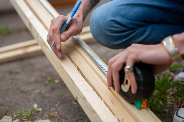 A man measures with a tape measure. Building made of wood. Wooden product.