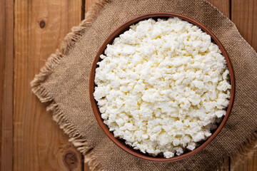 Cottage cheese on a burlap. Fresh cottage cheese in a bowl. Soft cheese on a wooden boards. Top view. Copy space