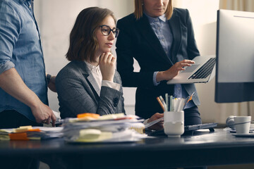 Beautiful business woman looking at computer monitor with her coworkers