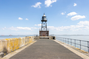 Fototapeta na wymiar lighthouse stands at the end of a pier at the North Sea