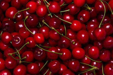 Obraz na płótnie Canvas Red cherries in full screen. The texture of cherries. A lot of red cherries. Fresh ripe sweet cherries with green stems