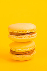 Sweet almond colorful yellow macaron or macaroon dessert cake isolated on trendy yellow modern fashion background. French sweet cookie. Minimal food bakery concept Copy space