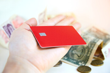 A red plastic credit card on a woman's palm. The concept of getting a loan and successful purchases with discounts, transferring paper money through an ATM