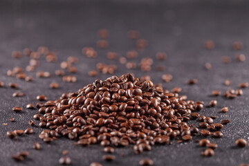 A pile of freshly roasted coffee beans on a dark background