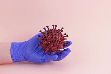 Pandemic covid19 concept.Hand in blue medical disposable rubber latex glove holds 3d model of coronavirus on pink background. protective disposable gloves against viruses, stopping the epidemic